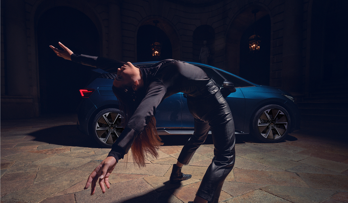 Person in Tanzpose vor einem CUPRA Born bei Nachtaufnahme